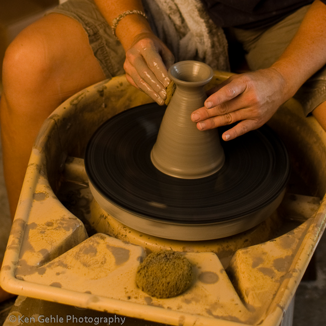 Woman's hands shaping a clay vase on a pottery wheel. 